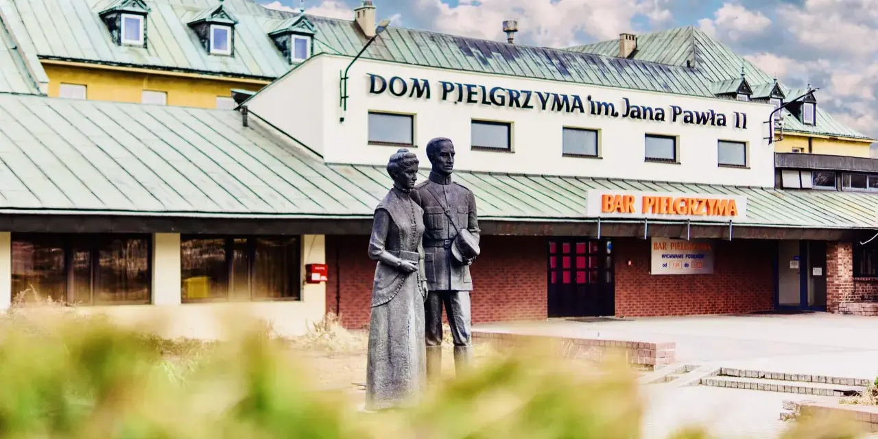 Pomnik przed Domem Pielgrzyma im. Jana Pawła II. Sprawdź ceny i godziny otwarcia baru.