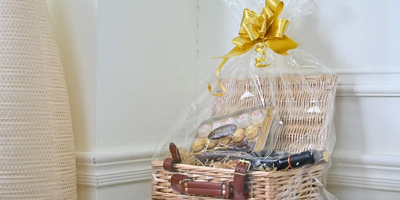 En vacker presentkorg med Ferrero Rocher-choklad och en flaska vin, inslagen i cellofan med en gyllene rosett.