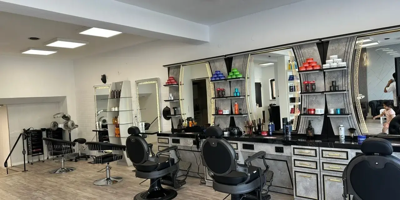 Friseurstuhl und Spiegel in einem modernen Salon mit Regalen voller Kosmetikprodukte.