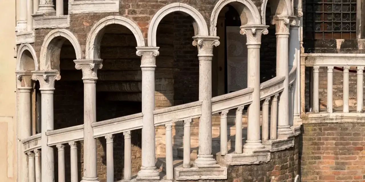 La scala Contarini a Venezia, con i suoi archi e colonne in marmo bianco, si snoda su una struttura in mattoni rossi, un'elegante spirale nel tempo.