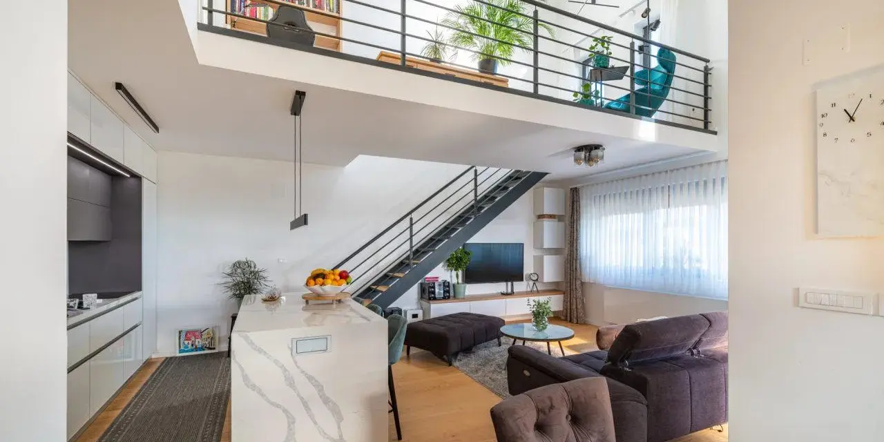 Soggiorno moderno con soppalco, libreria, cucina a isola e scala a vista. Ottime idee soppalco garage per sfruttare lo spazio.