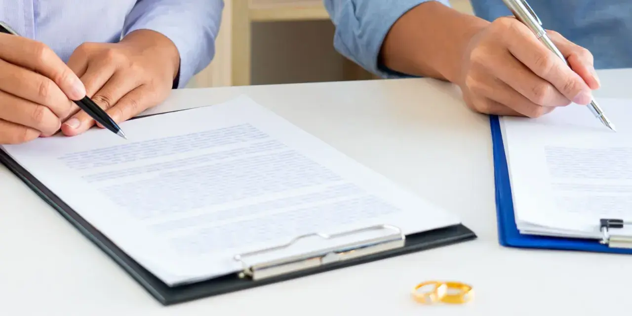 Deux mains signent des documents, symbolisant la fin d'une union. Attention au délai pour réclamer une prestation compensatoire.
