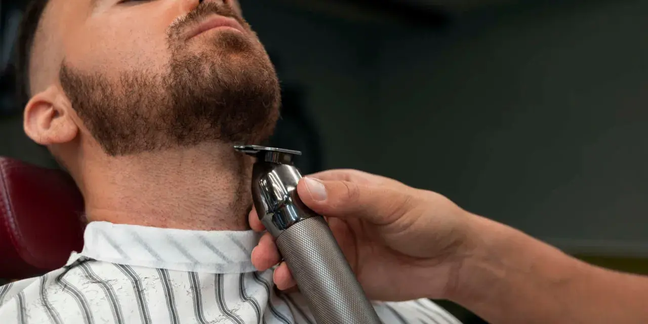 Barbero perfilando la barba ancla de un cliente con una recortadora.