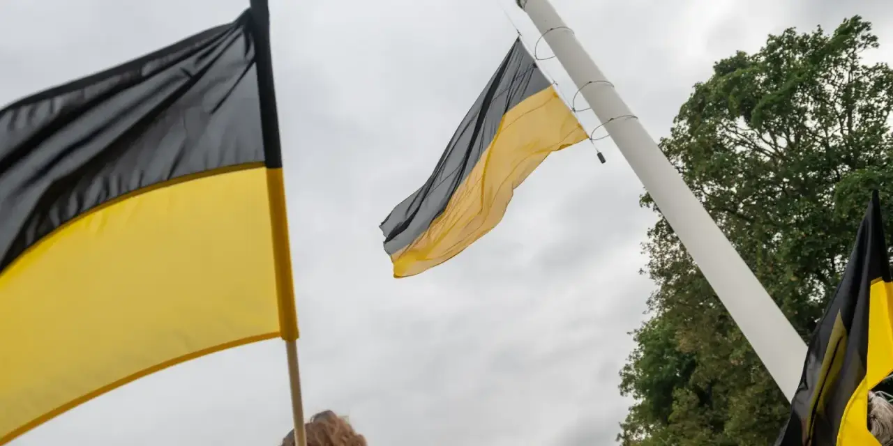 Flaga Kaszub powiewa na wietrze, symbol dumy i tożsamości.