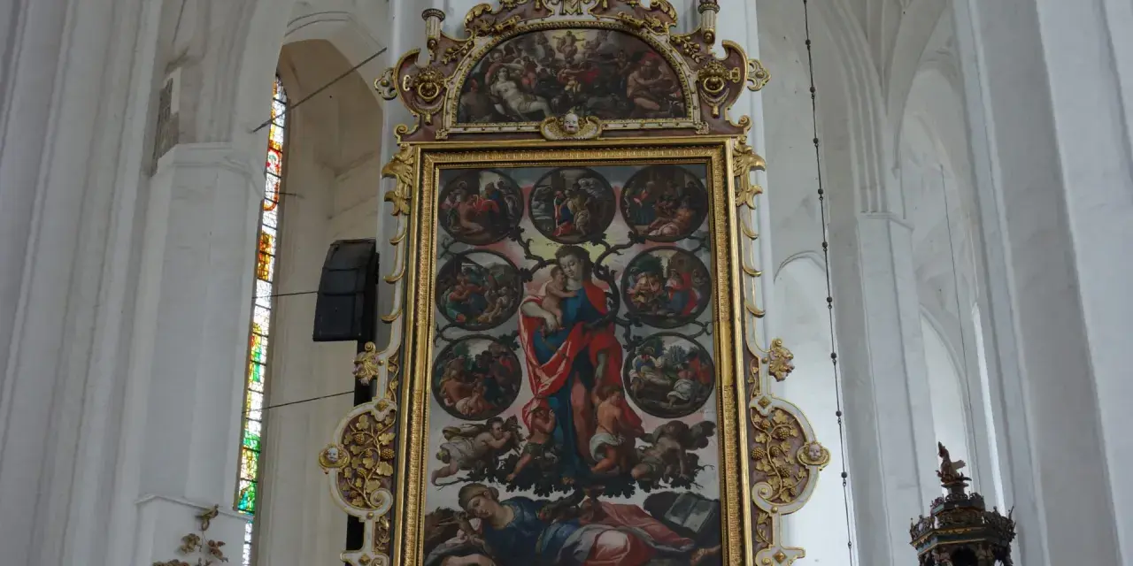 Wnętrze Bazyliki Mariackiej. Centralnie umieszczony, bogato zdobiony obraz przedstawia Matkę Boską z Dzieciątkiem i sceny z życia świętych.