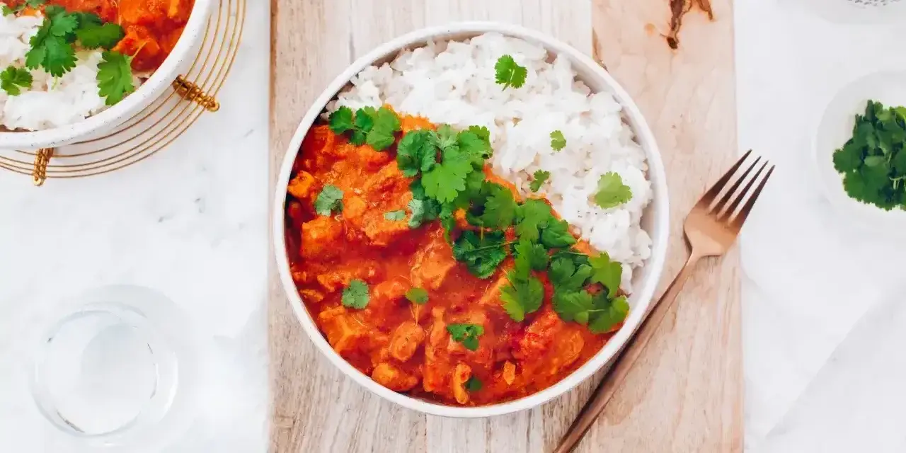 Pyszne czerwone curry z kurczakiem i ryżem, udekorowane świeżą kolendrą. Idealny przepis na obiad.