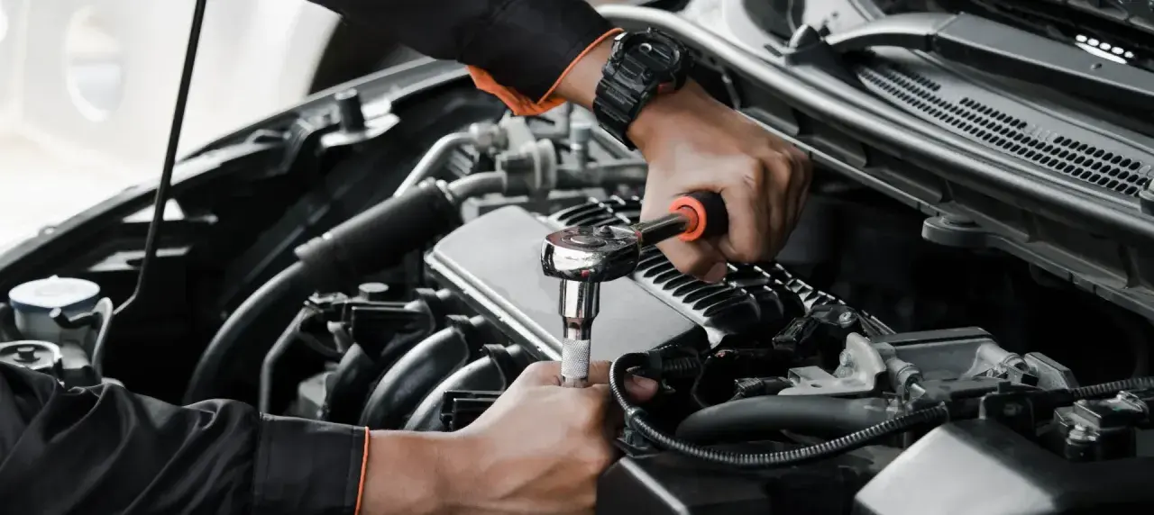 Mechanik wykonuje wymiana pompy paliwa krok po kroku, używając klucza nasadowego do odkręcenia śrub w silniku samochodu.