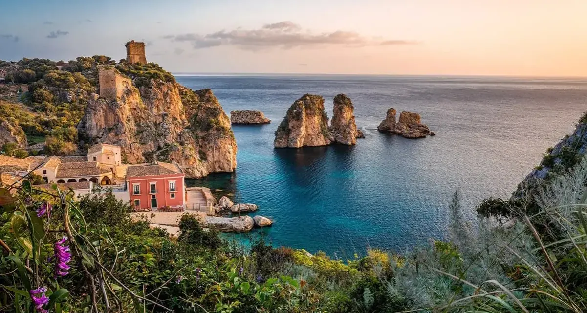 Traumhafte Küstenlandschaft mit Felseninseln, einem alten Turm und einem roten Haus. Perfekt für ein Auslandsjahr in Italien.