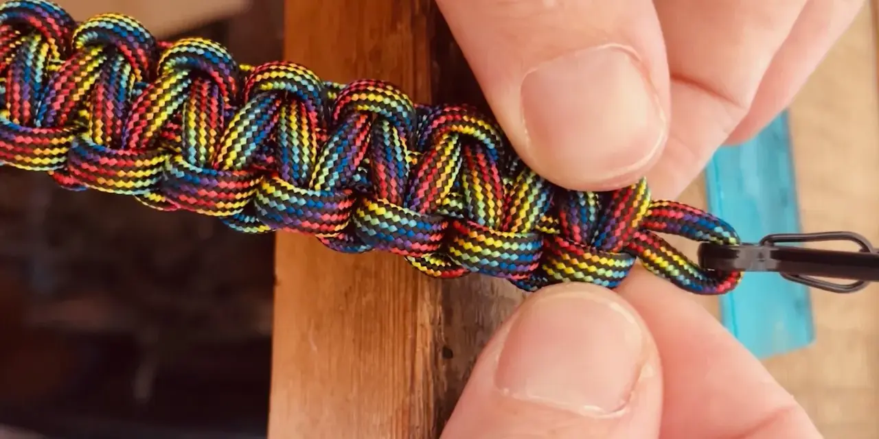 Mani che chiudono un braccialetto colorato con filo, mostrando come chiudere un braccialetto con filo.