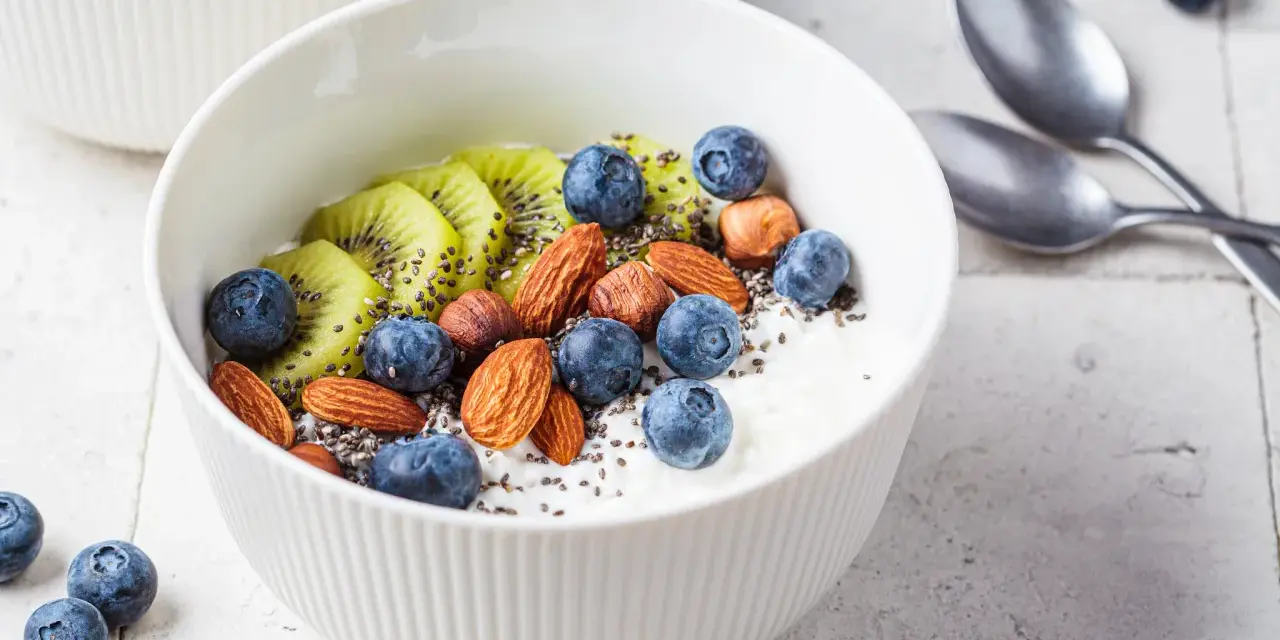 Schüssel mit Magerquark, Blaubeeren, Kiwi, Mandeln und Chiasamen. Perfekt für gesunde Magerquark Rezepte.