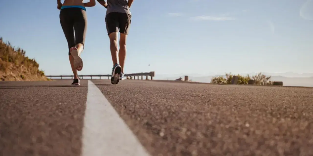 Coppia corre su strada asfaltata, godendosi la libertà e la velocità media corsa sotto un cielo azzurro.