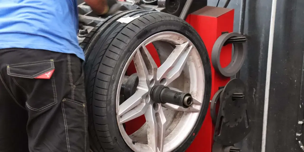Meccanico effettua la bilanciatura gomme su un'auto sportiva. L'operazione garantisce una guida fluida e sicura.