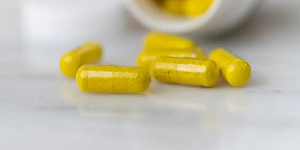 Capsule gialle sparse su una superficie chiara. La berberina a cosa serve? Potrebbe essere la risposta in queste capsule.