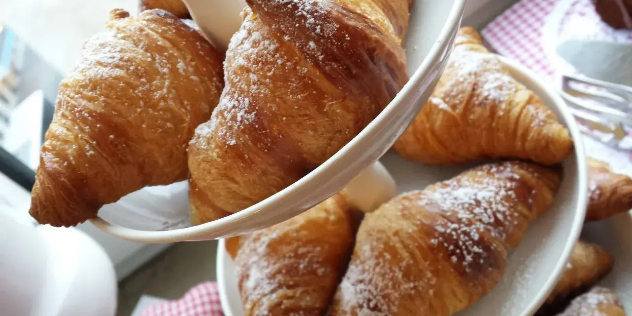 Cornetti fatti in casa, dorati e spolverati di zucchero a velo, invitano a una colazione golosa.