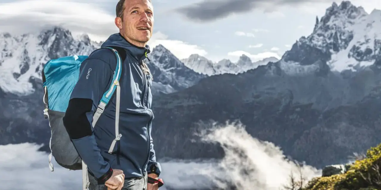 Randonneur contemplant les montagnes, son sac à dos léger prêt pour l'aventure.