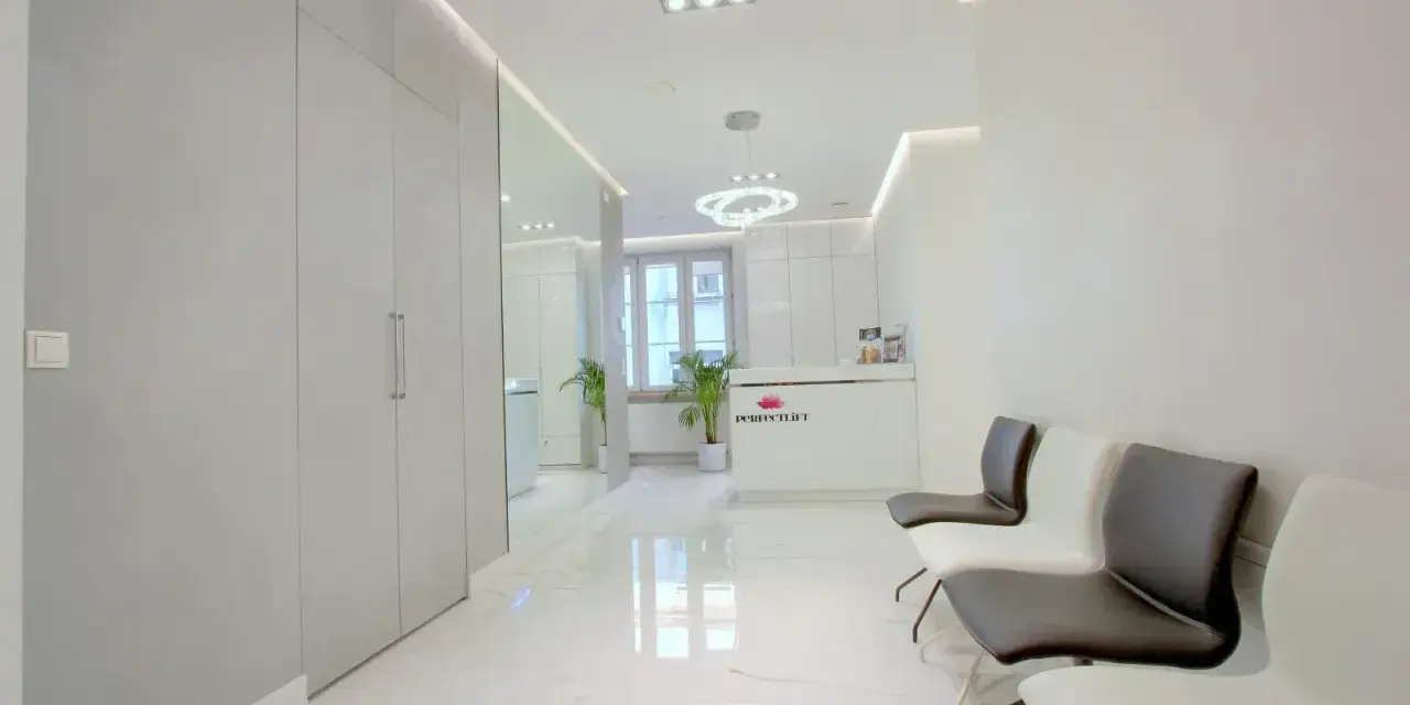 Nowoczesne wnętrze poczekalni kliniki estetycznej z białym recepcjonistą i wygodnymi fotelami.