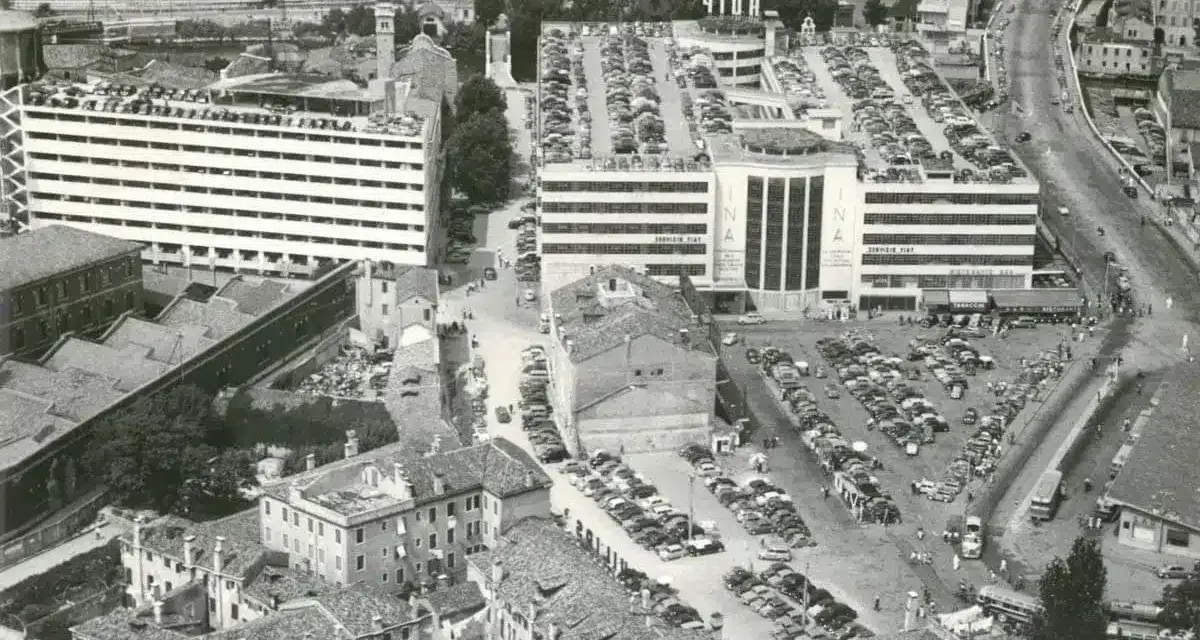 Vista aerea del parcheggio San Andrea a Venezia, con file di auto parcheggiate su più livelli e un edificio INA.