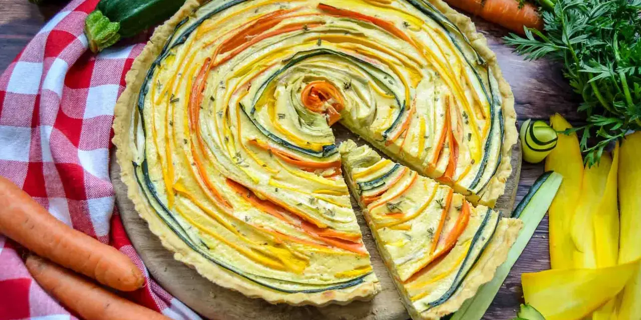 Eine bunte, vegetarische Quiche mit Zucchini und Karotten, kunstvoll im Kreis arrangiert. Frisch und lecker!