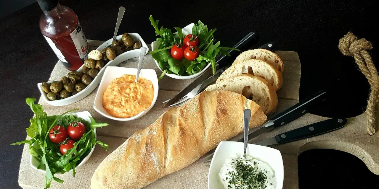 Eine köstliche italienische Brotzeit mit Baguette, Oliven, Tomaten, Rucola und Dips.