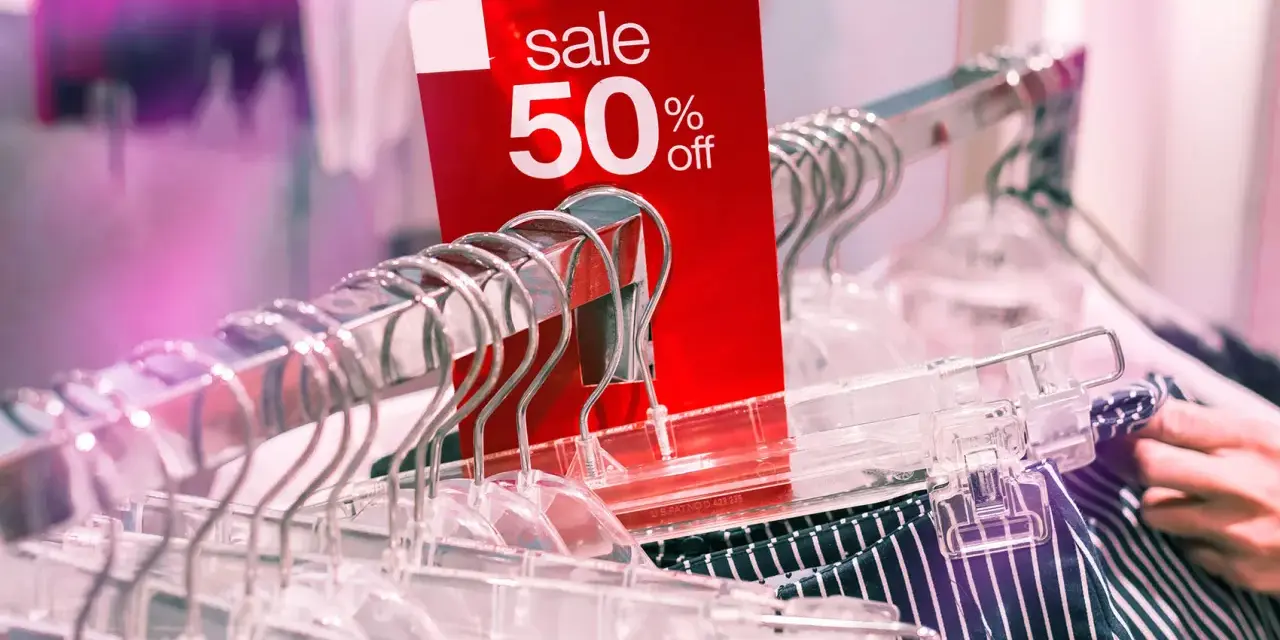 Czerwona metka "sale 50% off" na wieszakach. Czy to początek kompulsywnych zakupów?