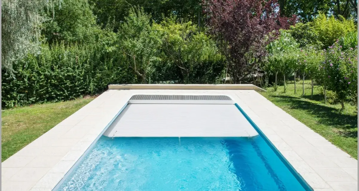 Piscina con cubierta automática, lista para reformar y disfrutar del verano. Rodeada de vegetación exuberante.