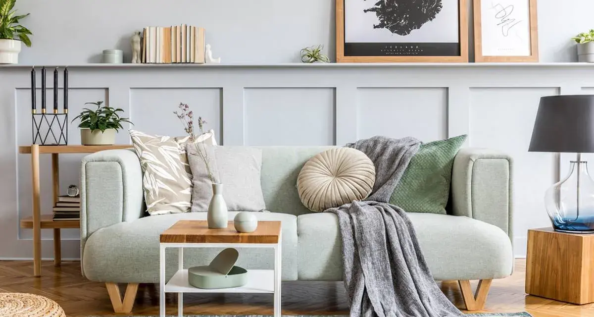 Un plaid gris drapé sur un canapé vert menthe, ajoutant une touche cosy. Idée pour comment mettre un plaid sur un canapé.