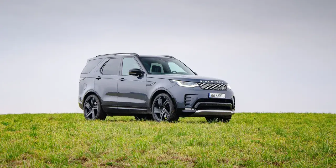 Szary Land Rover Discovery stoi na zielonej łące.