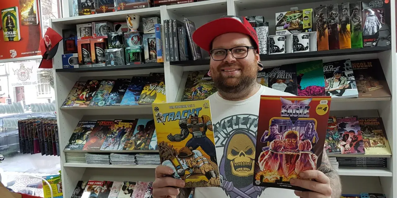 Mann mit Brille und roter Kappe hält zwei Comics in einem Comicladen.