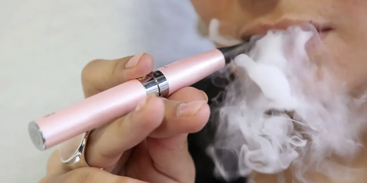 Persona vapea con un dispositivo rosa, liberando vapor. ¿Qué pasa si fumas vaper con nicotina?