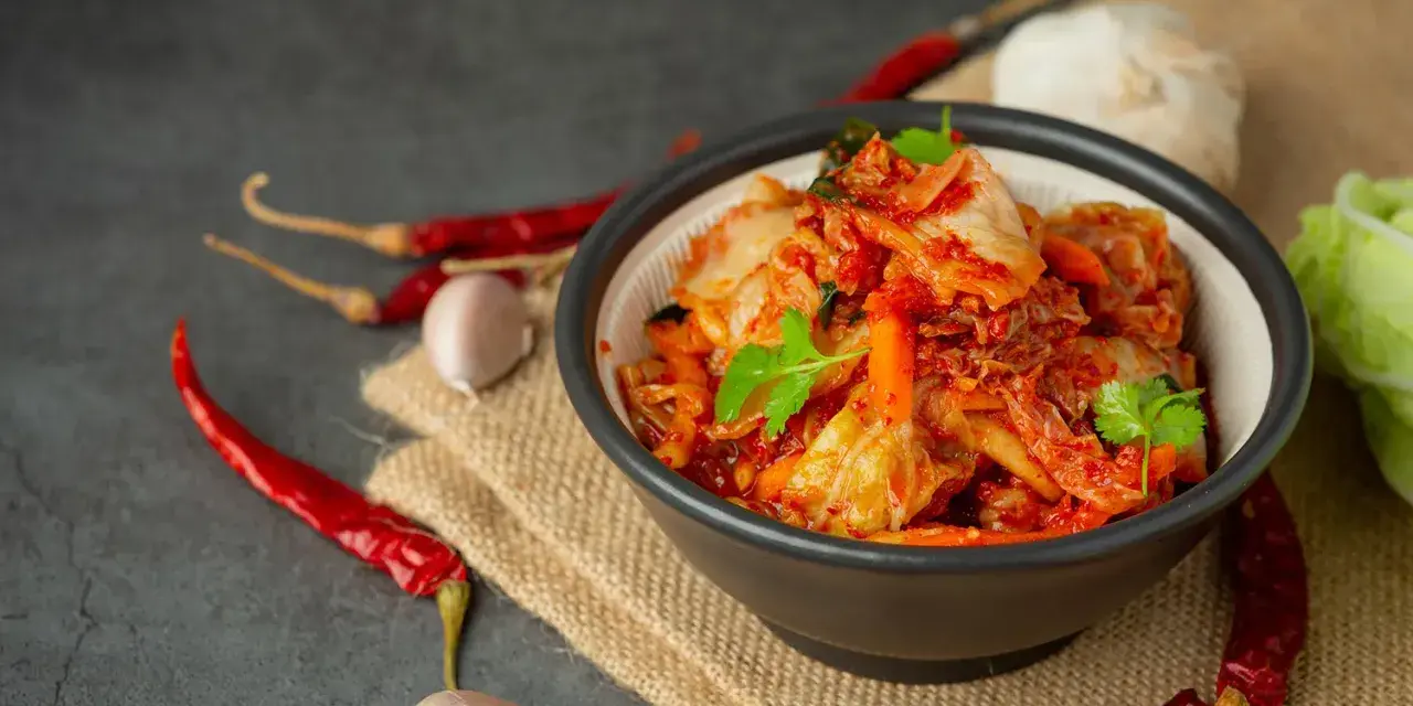 Miseczka z kimchi, obok suszone papryczki chili i czosnek.