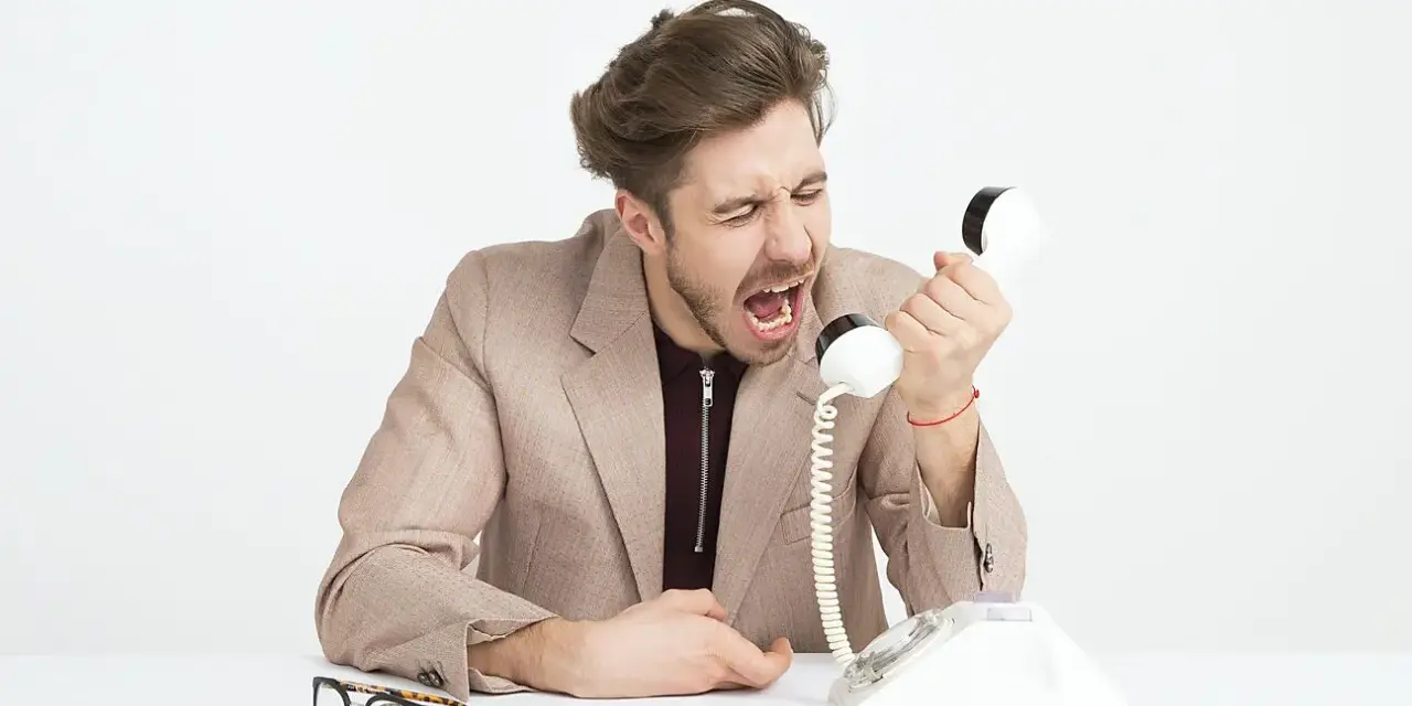 Mężczyzna w garniturze krzyczy do telefonu, jego twarz wyraża złość. Widać, że jest cholerykiem.