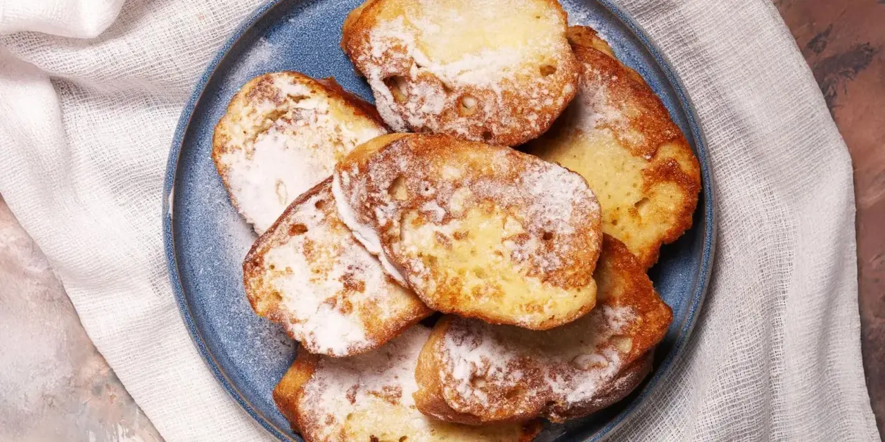 Ein Teller mit goldbraunem French Toast, bestäubt mit Puderzucker. Ein süßer Genuss für jeden Morgen.