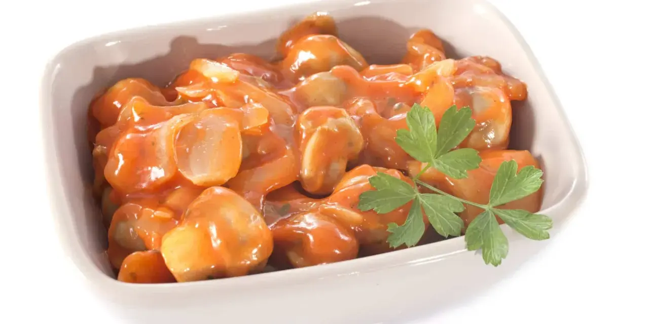 Champignons à la grecque, tendres et savoureux, baignant dans une sauce tomate onctueuse, garnie d'une touche de persil frais.