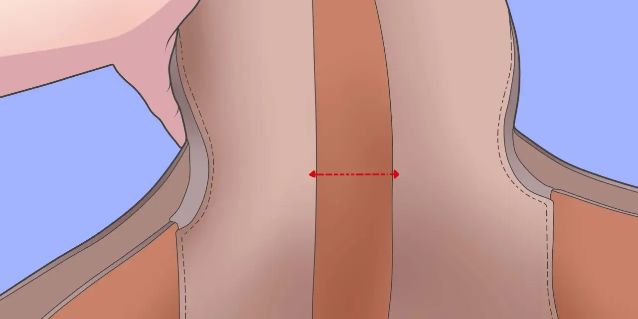 Une main tient une selle de cheval. Une flèche rouge indique comment mesurer la largeur de l'ouverture de la selle, une étape clé pour savoir comment mesurer une selle de cheval.