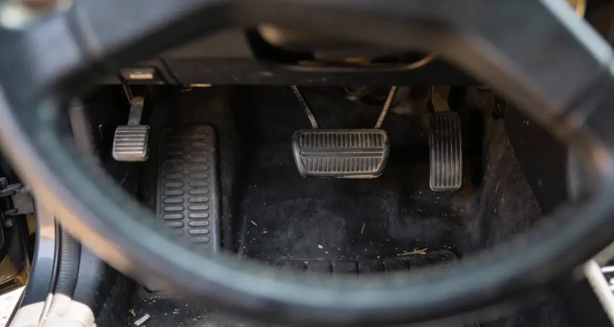 Widok na pedały samochodu. Sprzęgło, hamulec i gaz. Uważaj na jazdę na półsprzęgle, bo to męczy auto.