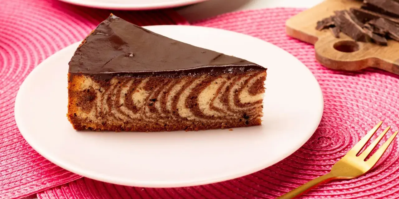 Ein Stück saftiger Zebrakuchen mit Schokoladenglasur auf einem Teller. Dieses Zebrakuchen Rezept ist ein Klassiker.