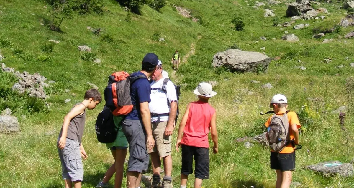 Famille en randonnée facile dans les Pyrénées, profitant d'un paysage verdoyant et rocheux.