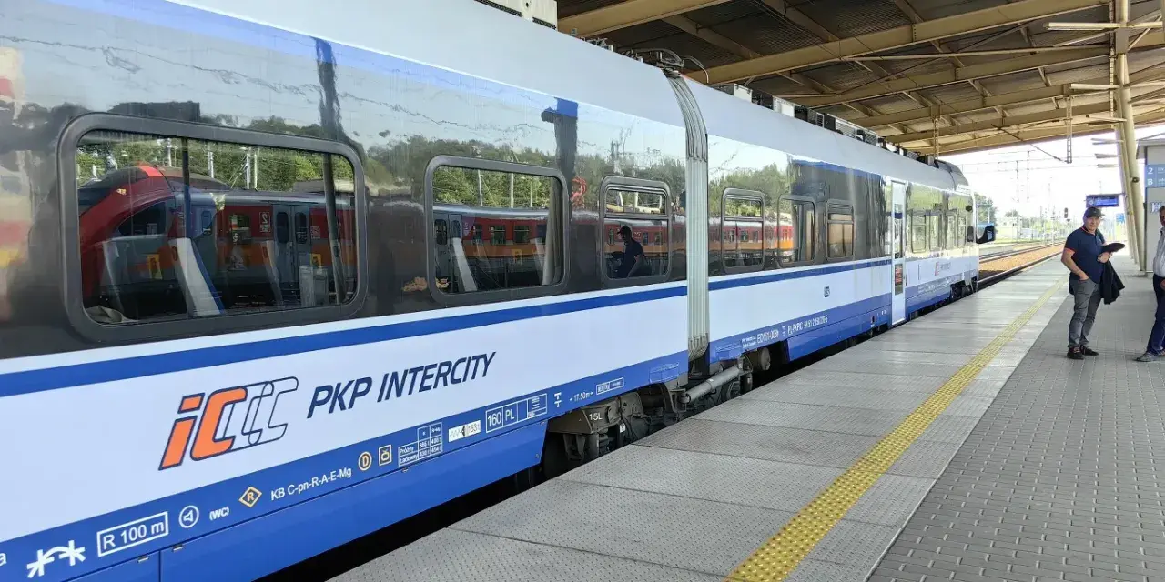 Pociąg PKP Intercity na peronie, z widocznymi oknami i logo przewoźnika.