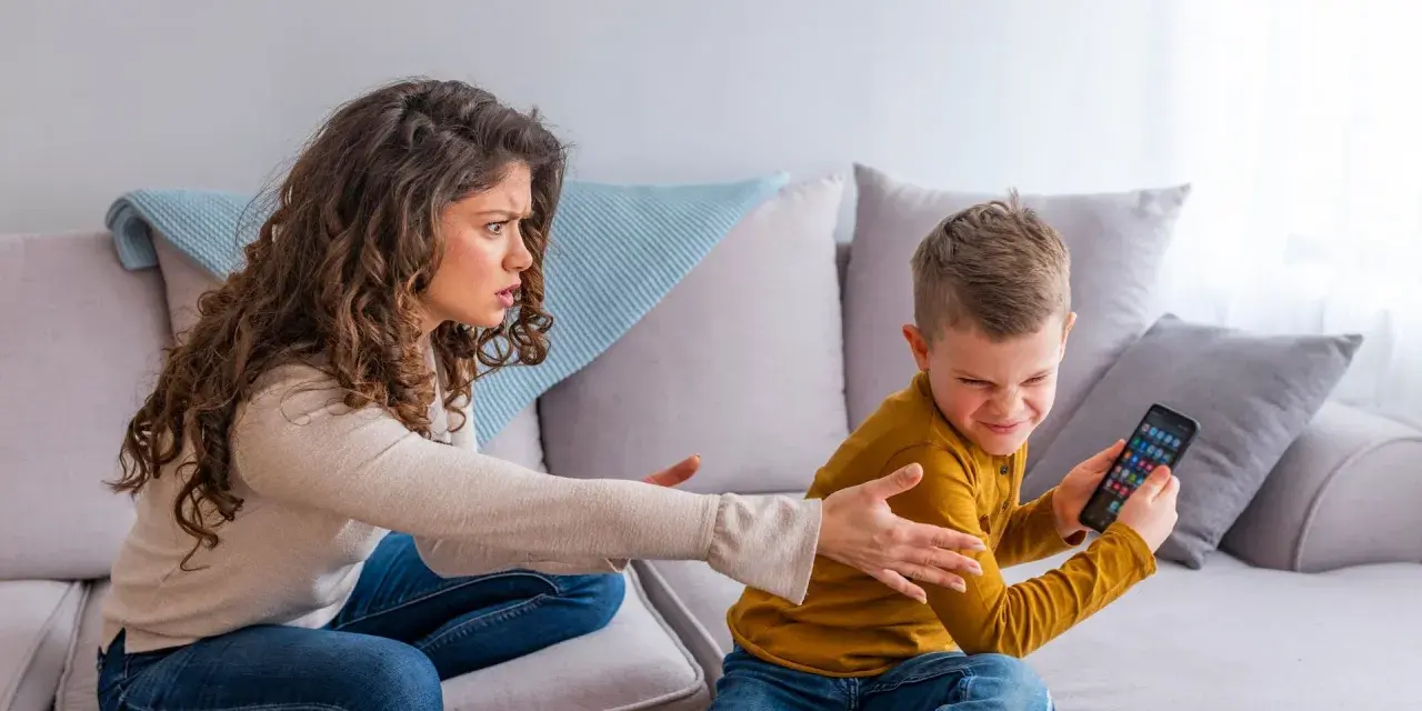 Genervte Mutter streitet mit Sohn, der sein Handy nicht abgeben will. Mögliche ADHS-Erziehungsfehler im Fokus.