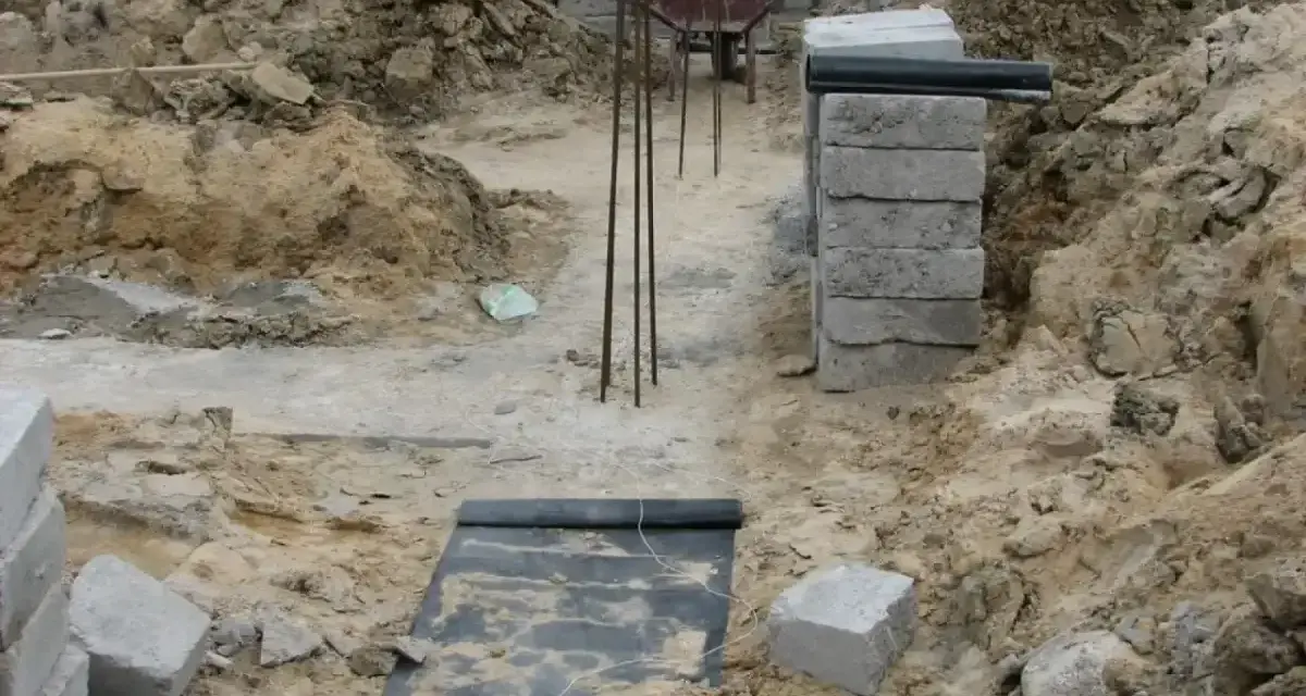 Wykonano wykopy pod fundamenty. Widać zbrojenie, betonowe bloczki i ziemię.