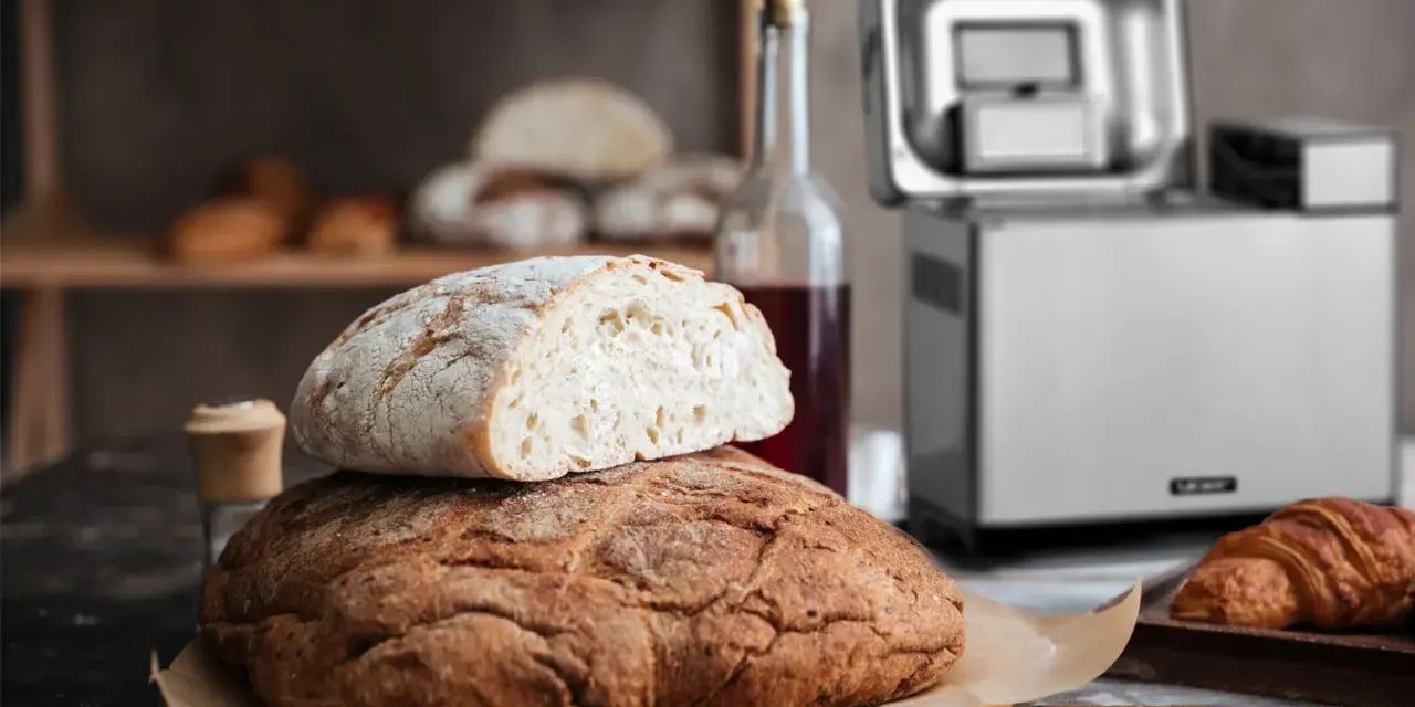 Chrupiący chleb z automatu, świeżo upieczony, czeka na śniadanie. Obok butelka wina i croissant.