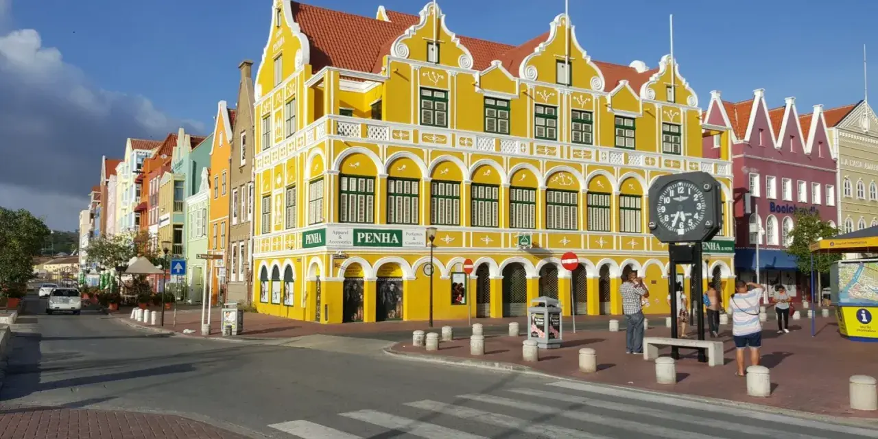 Kolorowe, zabytkowe budynki w stylu wielkich antyli, z dominującym żółtym budynkiem PENHA, tworzą malowniczy krajobraz miejski.