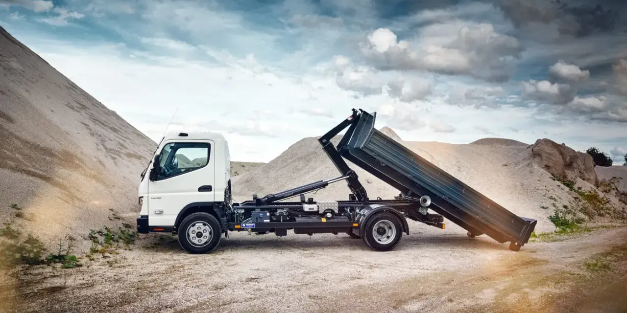 Biały Mitsubishi Canter z podniesioną skrzynią ładunkową na tle żwirowych hałd.