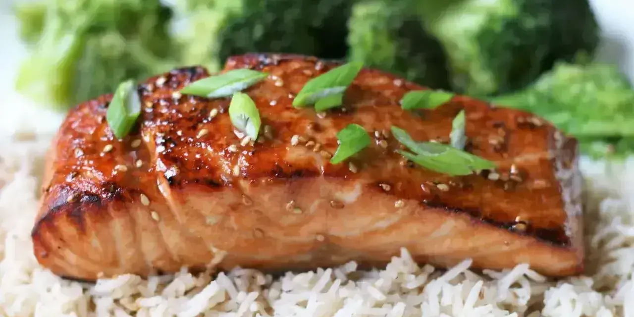 Łosoś w sosie teriyaki na ryżu z brokułami, posypany sezamem i szczypiorkiem. Pyszne danie.