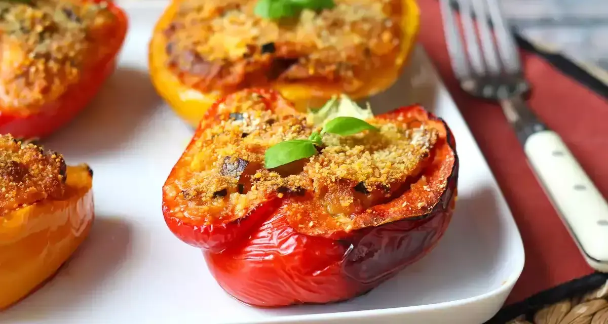 Peperoni ripieni al forno, un classico delle ricette con peperoni, serviti su un piatto bianco con una forchetta.