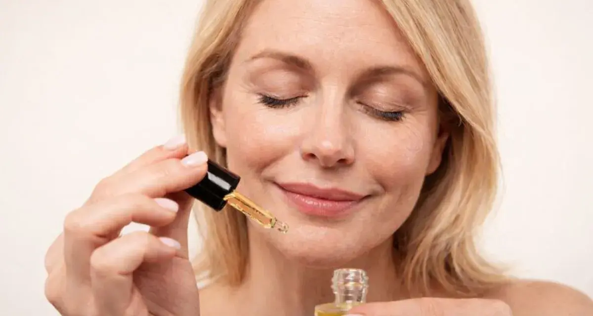 Kobieta z zamkniętymi oczami aplikuje serum z **retinolem**, dbając o skórę, by uniknąć efektów **solarium**.