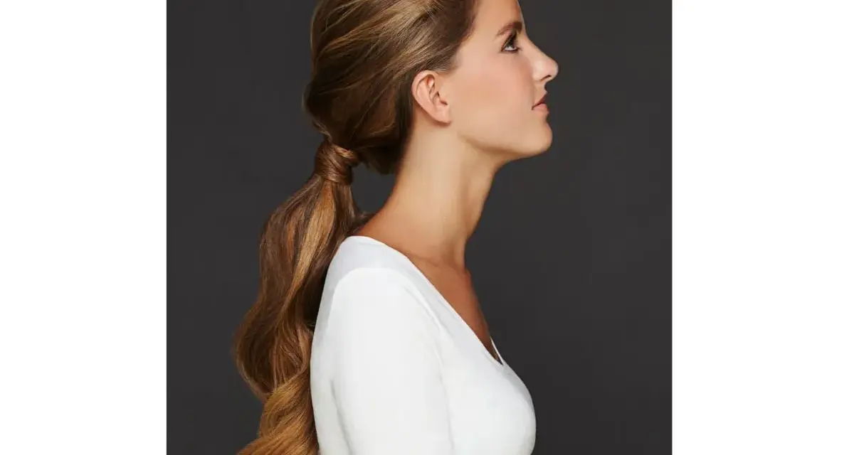 Capelli lunghi e mossi raccolti in una coda bassa, un'idea per semplici acconciature matrimonio invitata.