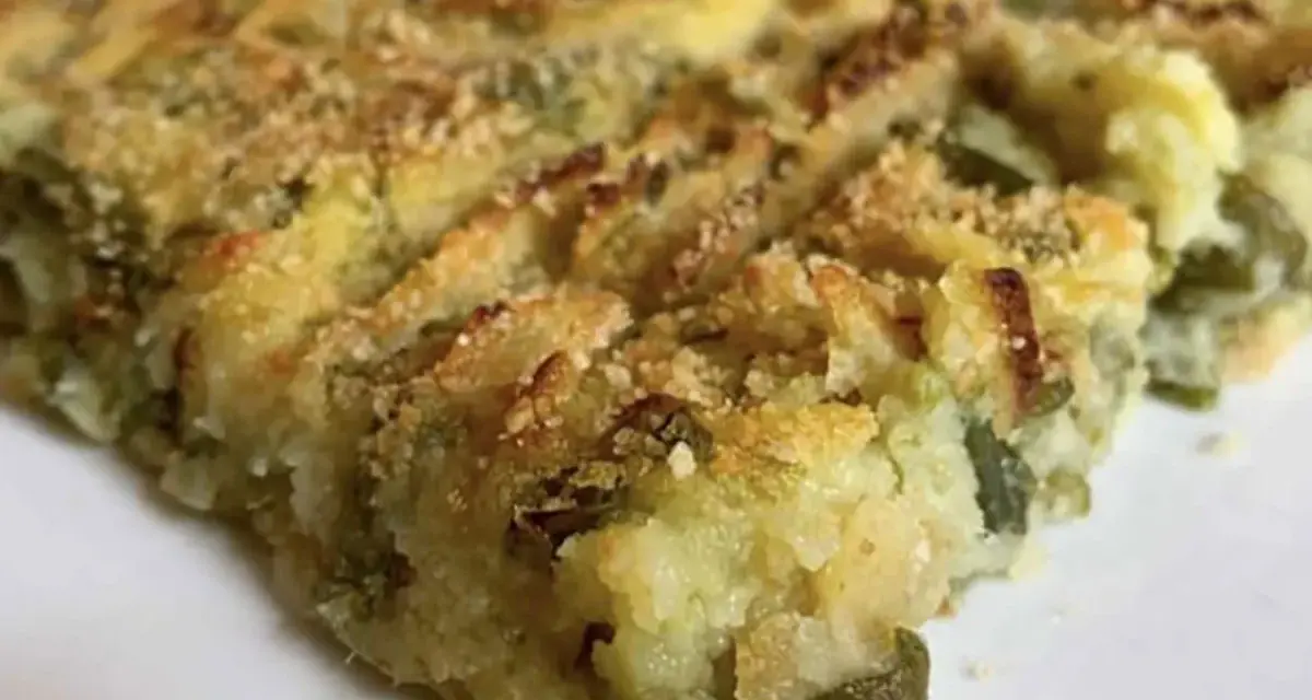 Fetta di polpettone genovese, con patate e verdure verdi, cotto al forno e cosparso di pangrattato croccante.