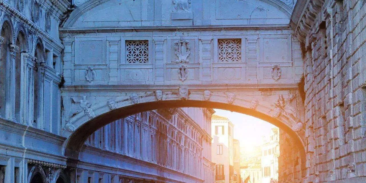 Il Ponte dei Sospiri a Venezia, con la sua architettura barocca e le finestre decorate, si staglia contro il cielo al tramonto, offrendo uno scorcio suggestivo sui canali.