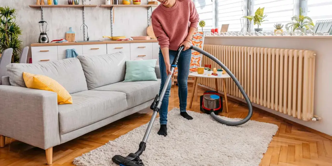 A woman vacuums a fluffy rug, demonstrating how to clean a rug for a fresh, tidy living room.